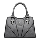 Bolsa feminina cinza com texturas em relevo, alças estruturadas e detalhes de costura em leque