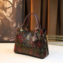 Bolsa feminina com estampa floral em relevo, alças de couro e ferragens douradas