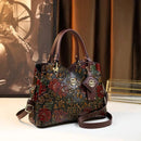 Bolsa de couro preta com estampa floral em relevo, alças marrom e detalhes dourados