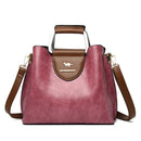 Bolsa feminina de couro sintético bordô com alça tiracolo, detalhes em marrom e logotipo de canguru