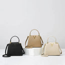 Três bolsas de couro estruturadas em preto, bege e off-white com detalhe V dourado