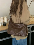 Bolsa hobo de couro marrom com alça de ombro, usada com moletom bege