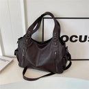 Bolsa feminina hobo em couro marrom escuro com alças reforçadas, zíperes metálicos frontais e bolso lateral.