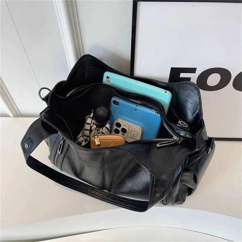 Bolsa feminina hobo em couro preto com interior espaçoso, acomodando celular, carteira, chaveiro e outros objetos pessoais.