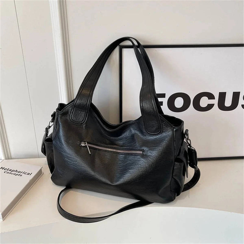 Bolsa feminina hobo em couro preto com bolso frontal com zíper, alças largas reforçadas e design clássico.