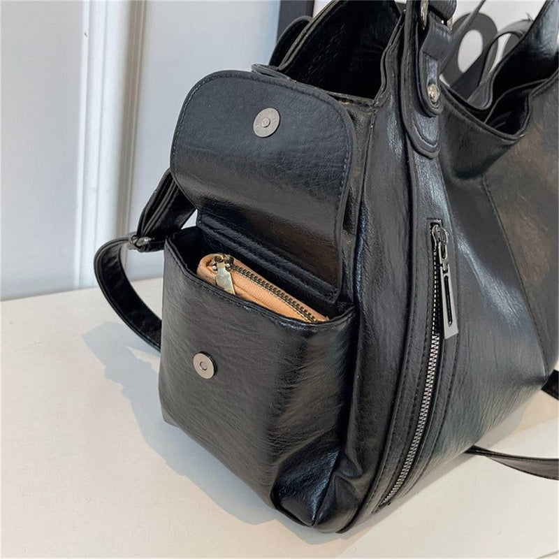 Detalhe do bolso lateral da bolsa feminina hobo em couro preto, com botão de fechamento e zíper metálico.