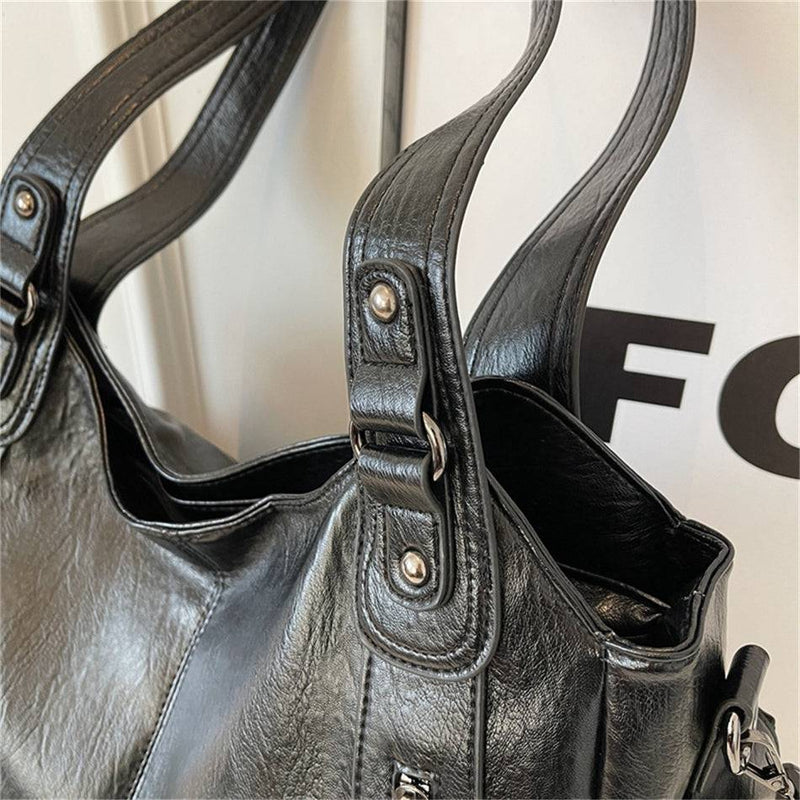 Detalhe da alça da bolsa feminina hobo em couro preto, com costura reforçada e acabamento metálico.