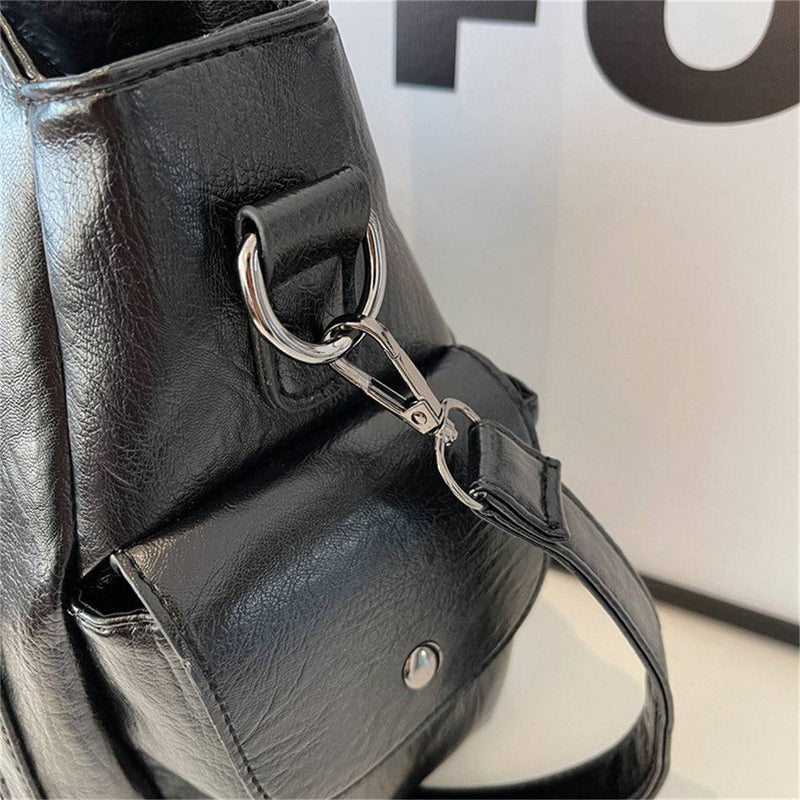 Detalhe da bolsa feminina hobo em couro preto, com fecho metálico de engate e acabamento de alta qualidade.