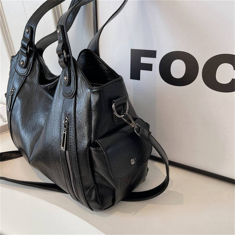 Bolsa feminina hobo em couro preto com detalhes de zíper, bolso lateral com botão e alças reforçadas.