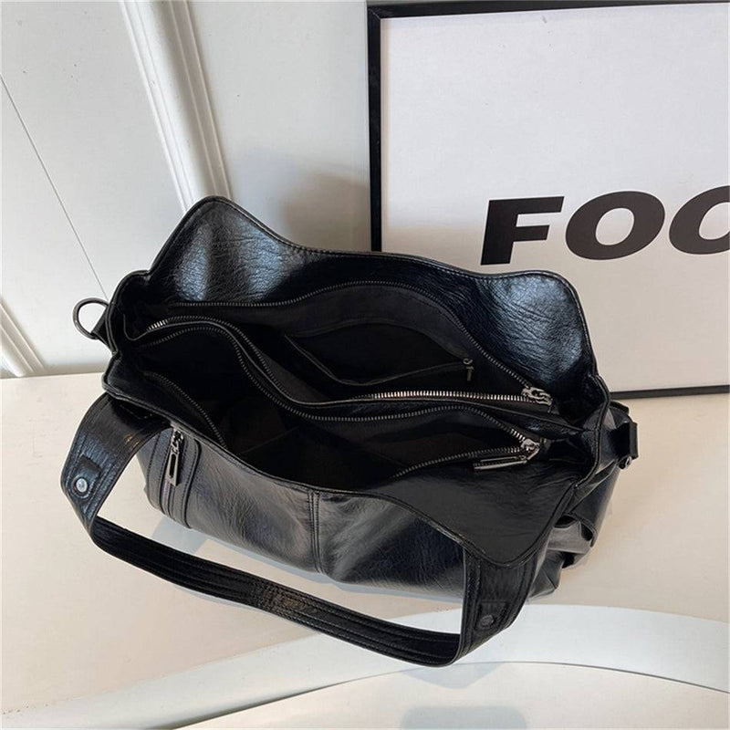 Interior espaçoso da bolsa feminina hobo em couro preto com divisórias e bolsos com zíper para organização.