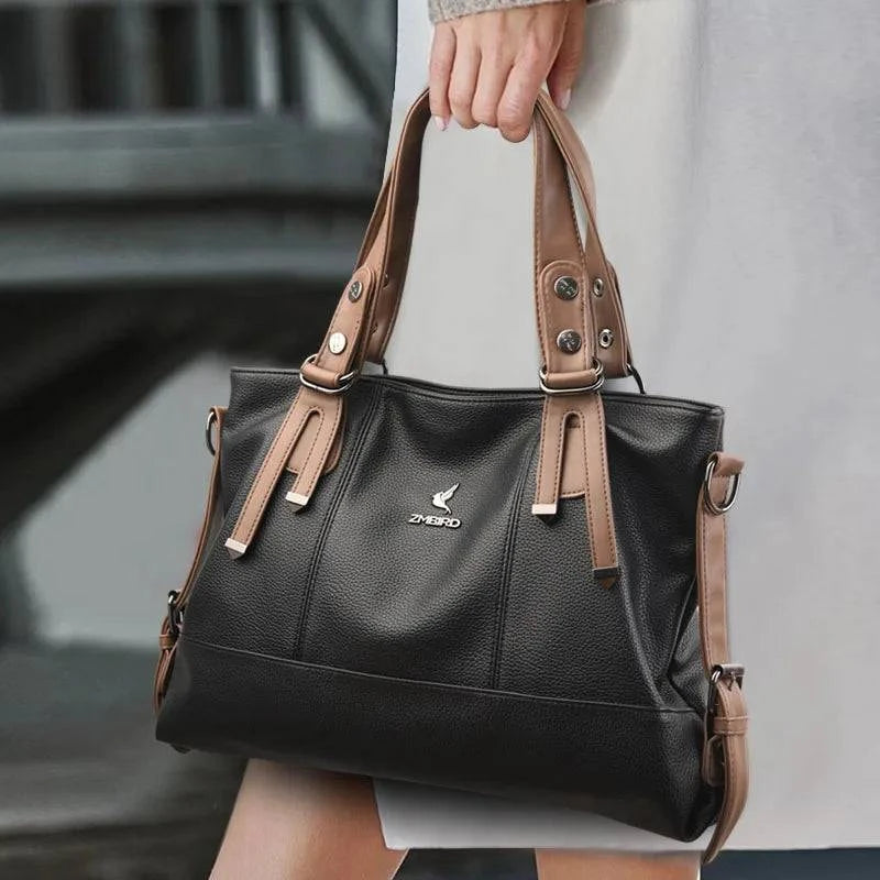 Bolsa Feminina de Mão Couro Genuíno preta e marrom, com detalhes de alças contrastantes. Design estruturado e ferragens metálicas. Elegante e versátil.