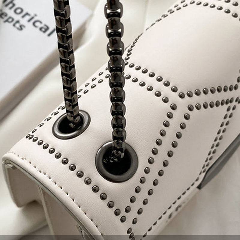 Detalhe da Bolsa Feminina Tiracolo Estruturada creme, mostrando o acabamento com rebites, os ilhós da alça de corrente escura e a textura do material.