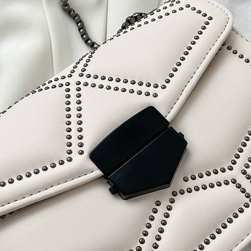 Detalhe da Bolsa Feminina Tiracolo Estruturada na cor creme, mostrando de perto o design matelassê com rebites, o fecho geométrico preto e a textura sofisticada.
