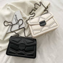 Bolsas tiracolo estruturadas: versões preta e creme com design matelassê, rebites e fecho geométrico