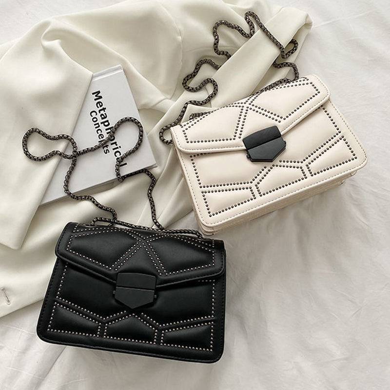 Duas Bolsas Femininas Tiracolo Estruturadas, uma preta e outra creme, ambas com design matelassê de rebites, fecho geométrico moderno e alça de corrente escura, destacando as opções de cores.