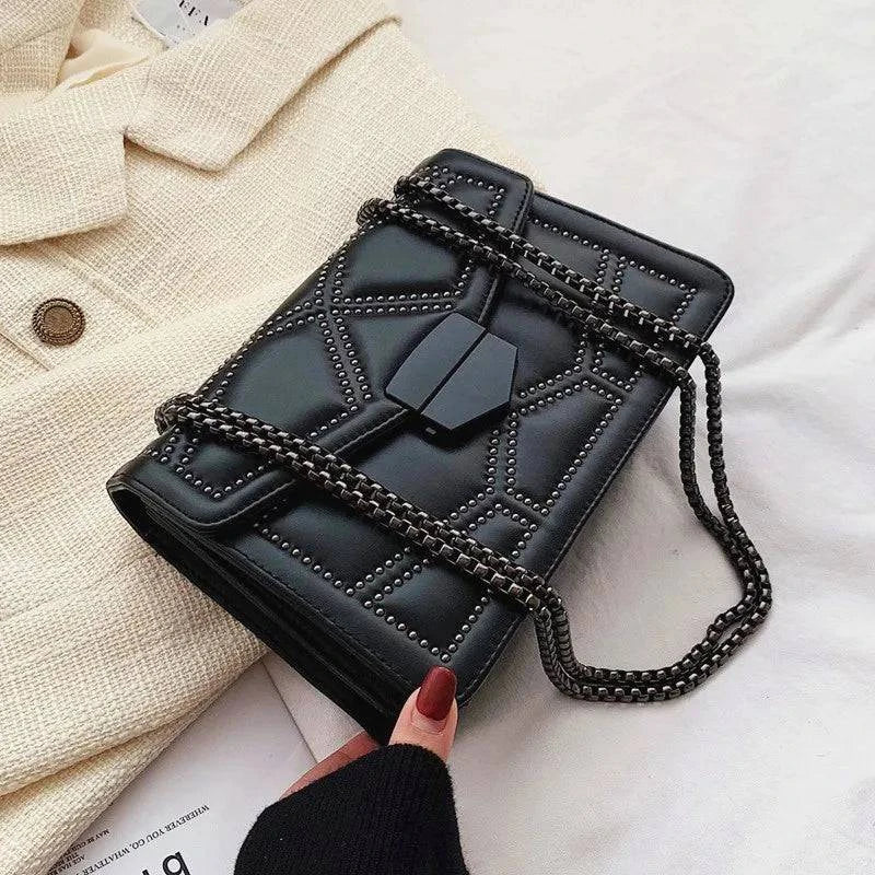 Bolsa Feminina Tiracolo Estruturada preta com design matelassê de rebites, fecho geométrico central e alça de corrente grafite, ideal para um estilo moderno e versátil.