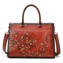 Bolsa tote de couro vermelho-ferrugem com desenho floral em relevo dourado