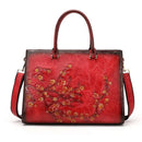 Bolsa tote vermelha de couro com relevo floral dourado e detalhes em laranja