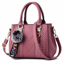 Bolsa tote média rosa estruturada com textura chevron, alça transversal e pompom cinza com detalhe LOVE