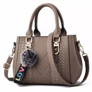 Bolsa tote taupe estruturada com textura chevron, alças duplas e chaveiro pompom colorido