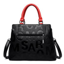 Bolsa feminina preta com padrão de letras em relevo, alças vermelhas e bolso com zíper frontal