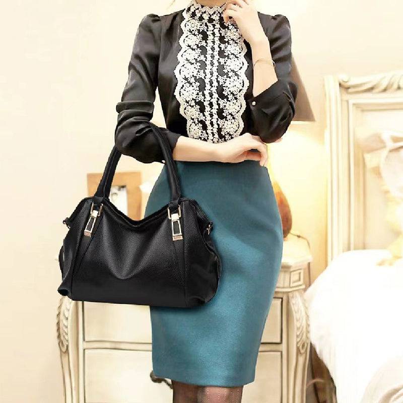 Mulher elegante com blusa de renda e saia azul usando bolsa hobo preta de couro sintético, destacando as alças de mão e o formato moderno da bolsa.