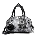 Bolsa de Mão Monarca cinza e preta, textura de cobra e croco. Design semiesférico, alças pretas, charm de rosa. Elegante e sofisticada.