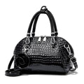 Bolsa de Mão Monarca preta, couro com textura croco brilhante. Design semiesférico, alças duplas, charm de rosa. Elegante e sofisticada.