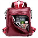 Mochila de couro vinho com compartimento aberto mostrando tablet, celular e garrafa