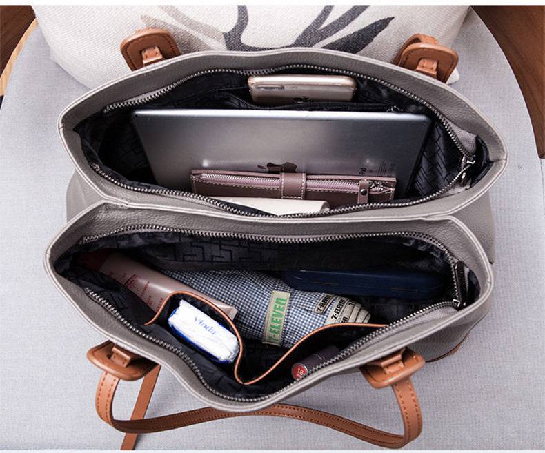 Interior da bolsa de ombro feminina em couro legítimo cinza com divisórias e compartimentos, contendo tablet, carteira e itens pessoais.
