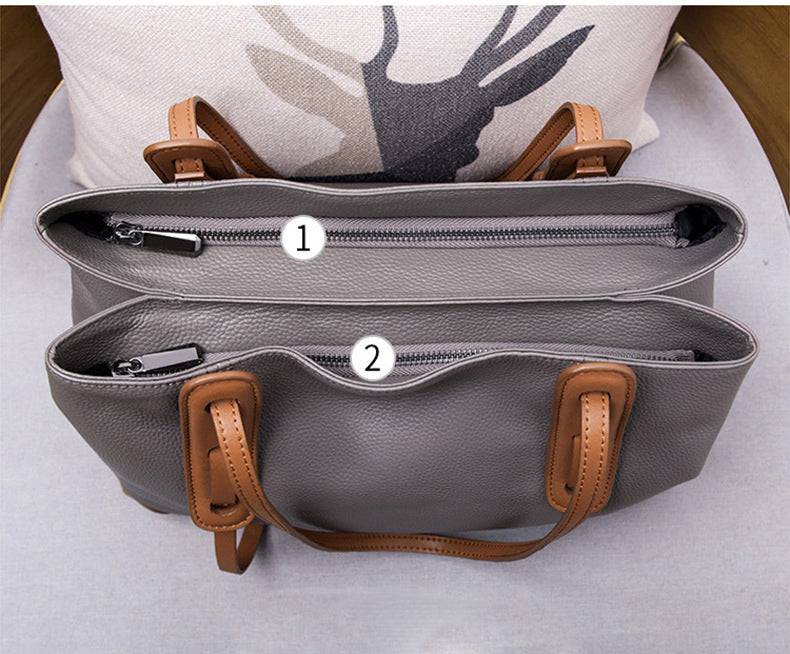 Visão superior da bolsa de ombro feminina em couro legítimo cinza com alças marrons, destacando os compartimentos internos numerados.
