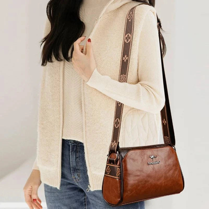 Shoulder Bag Bolsa Feminina de Couro marrom-caramelo. Alça estampada e logo de canguru. Usada por modelo em look casual. Versátil e prática