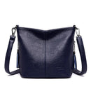 Bolsa tiracolo de couro azul marinho com textura granulada, alça ajustável e detalhes em corrente