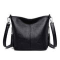 Bolsa tiracolo de couro feminina Ladies preta com acabamento granulado, design macio e alça transversal ajustável com detalhes de corrente e borlas, em vista frontal.
