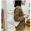 Mulher com blazer marrom usando bolsa tote acolchoada branca de couro sintético com alça de corrente dourada no ombro, estilo casual elegante.