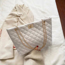 Bolsa tote branca acolchoada com alça de corrente dourada e fecho metálico.