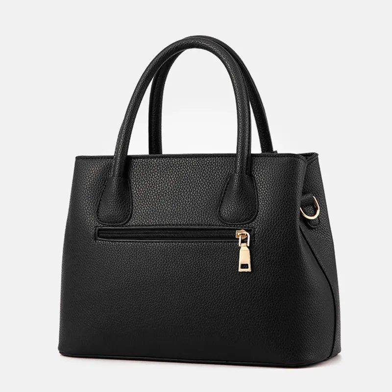 Parte traseira da bolsa tote de couro feminina Eliza preta, destacando o bolso com zíper dourado e o design minimalista do couro granulado.