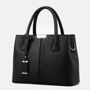 Bolsa tote preta com textura em couro, alças duplas e detalhe metálico frontal