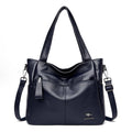 Bolsa tote de couro feminina Lara azul marinho com alças de ombro e alça transversal, múltiplos bolsos frontais com zíper e logotipo de canguru, design espaçoso e acabamento suave.