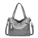 Bolsa tote feminina cinza com alças duplas, alça transversal e bolso frontal com zíper.