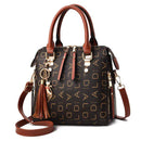 Bolsa tote estruturada marrom com padrão geométrico dourado, alças e tiracolo de couro cognac, charm com borla.