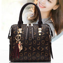 Bolsa tote estruturada preta com padrão de monograma dourado e chaveiro decorativo