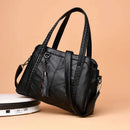Bolsa tote preta estruturada com alças acolchoadas, costura em V e tassel