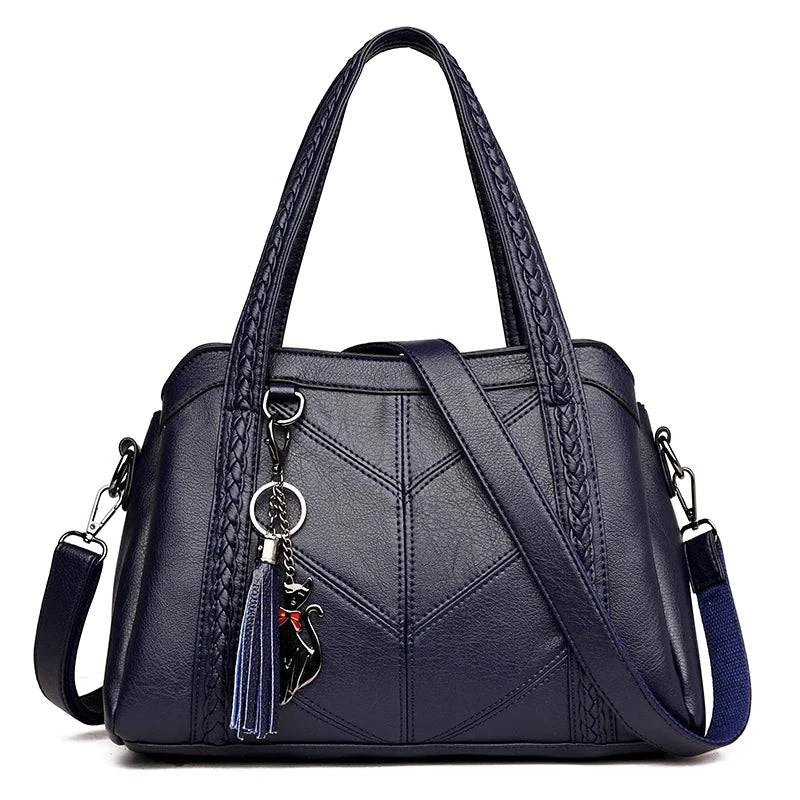Bolsa tote estruturada azul-marinho em couro sintético com detalhes de costura em "V" e alças de mão trançadas.