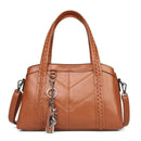 Bolsa tote estruturada marrom caramelo com textura de couro, alças de mão trançadas e detalhe de chaveiro, ideal para o dia a dia.