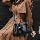 Bolsa tote estruturada de couro preto com alças de mão e alça transversal, usada com trench coat bege