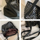 Bolsa tote preta de couro com rebites metálicos prateados, alça de ombro e interior em tons de vinho