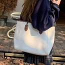 Bolsa tote branca de couro com alças marrom, usada ao ombro