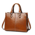 Bolsa Tote Feminina Couro Legítimo Velvet marrom. Couro com acabamento brilhante, costura branca, alças e ferragens metálicas. Elegante e estruturada.