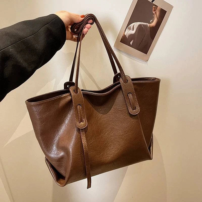 Bolsa Tote Feminina em couro marrom com alças longas, detalhe de laço e acabamento liso
